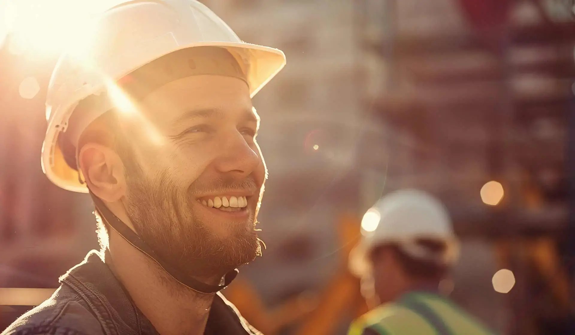 Lächelnder Bauarbeiter mit Schutzhelm im Sonnenlicht – Symbolbild für steuerfreie Inflationsausgleichsprämie im Baugewerbe bis Ende 2024