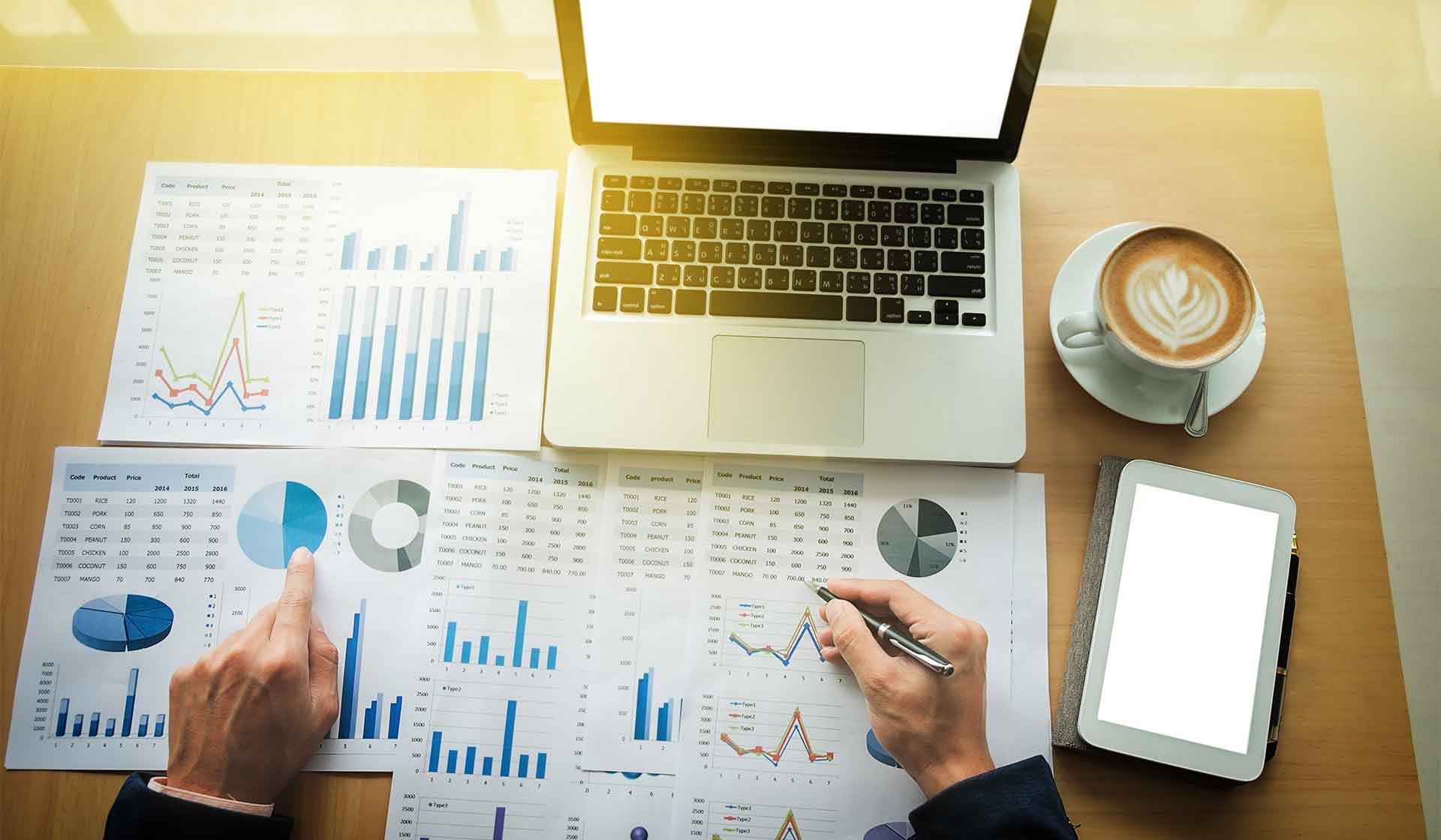 Kostenanalyse und Controlling im Baubetrieb – Laptop, Tablet, Auswertungen und Kaffeetasse auf Schreibtisch