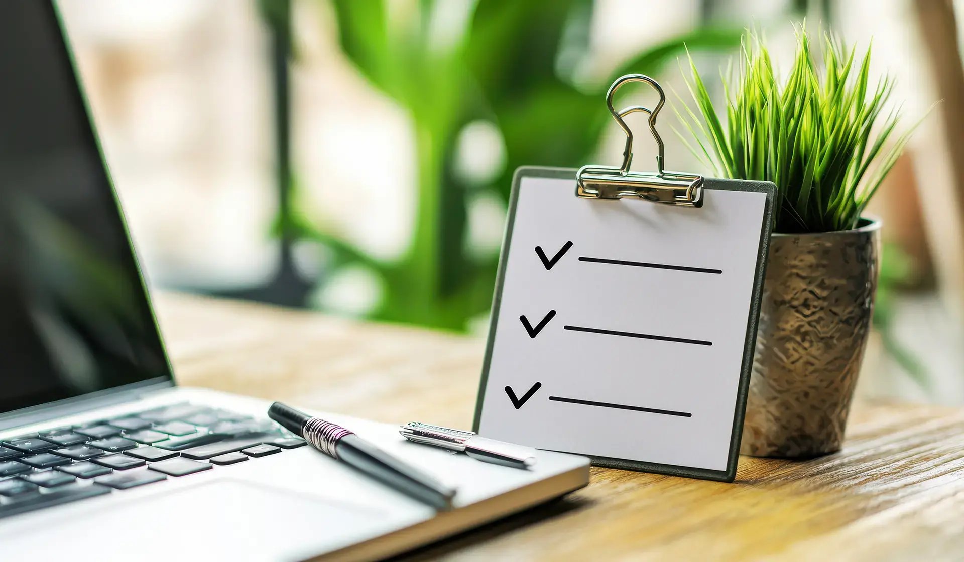 Laptop mit Stift, Checkliste und Pflanze auf einem Schreibtisch – digitale Erfolgstipps und Checklisten für Bauunternehmen und Büros in Deutschland