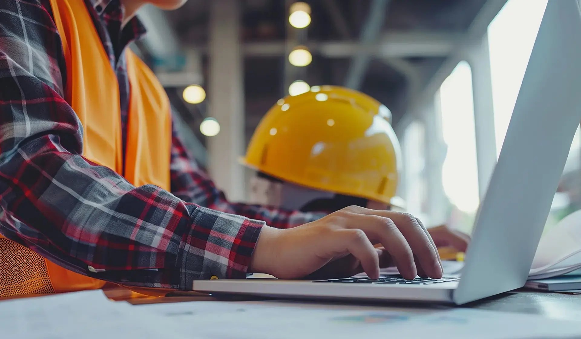 Mitarbeiter in Warnweste tippt auf Laptop – Thema Datensicherheit auf der digitalen Baustelle